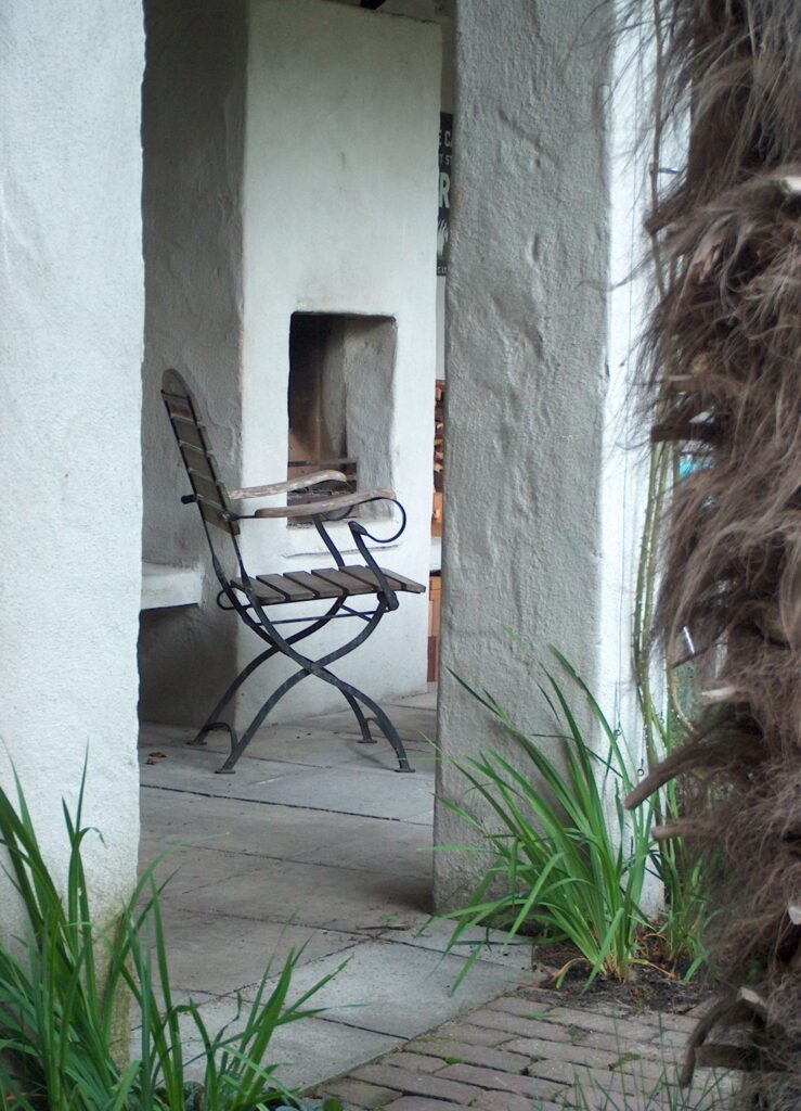 Zuid-europese sfeer door grof gestucte veranda, haard met zitplek en palm