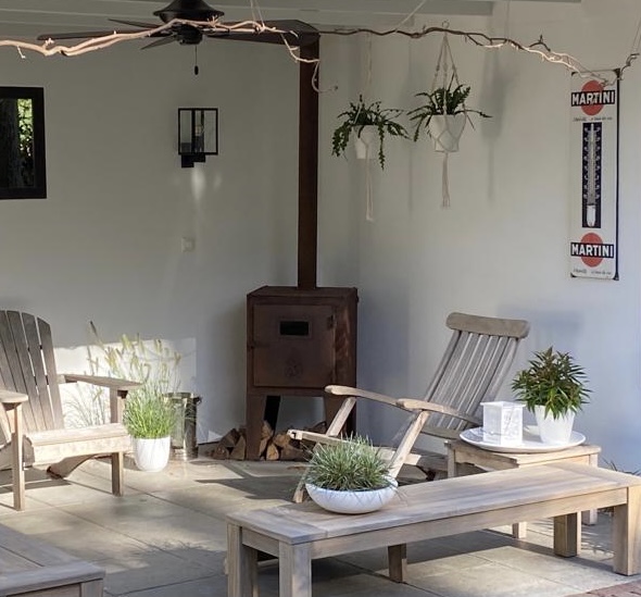 Veranda met houtkachel en vergrijsde bankjes en luie stoelen + 2 zijden tuinzicht