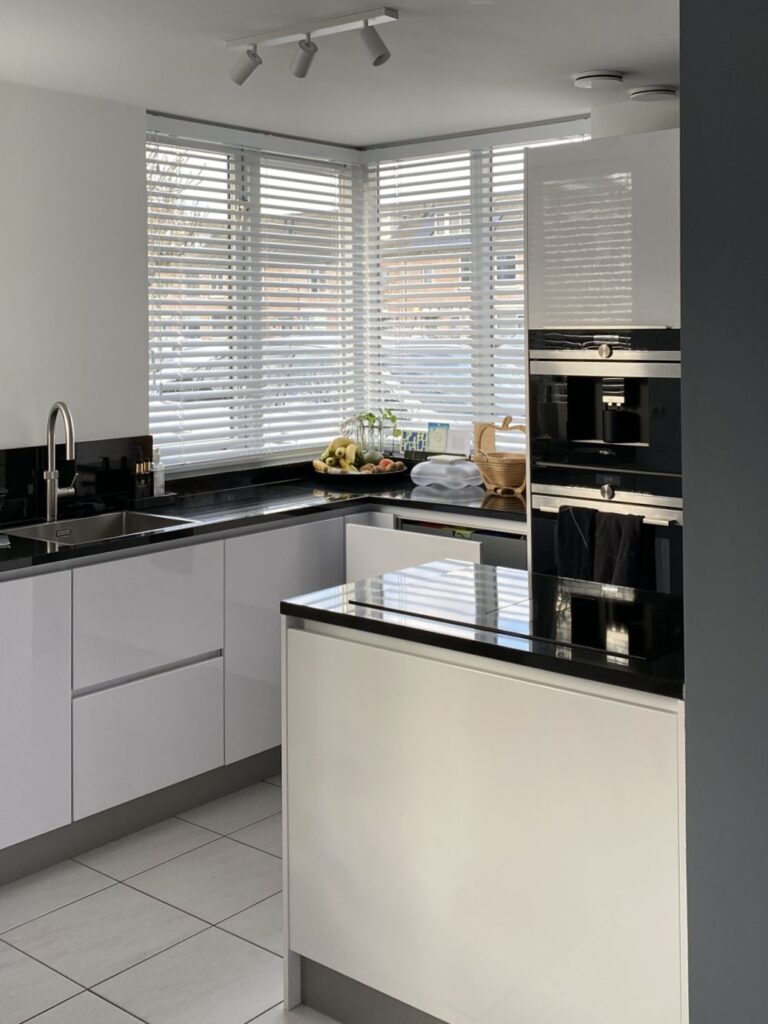 NIEUW zwart-witte keuken met koelkast tegen achterwand en kookeiland zorgt voor ruimte