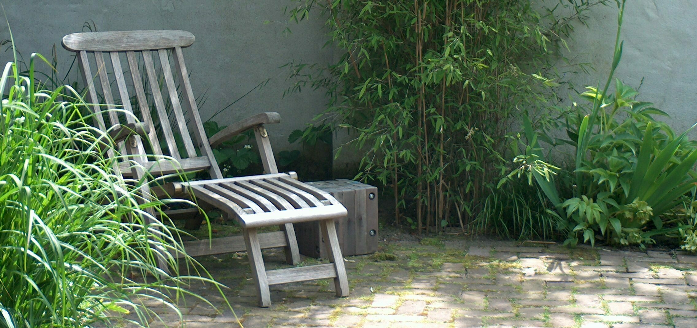 lekkere houten ligstoel - gestucte muren, oude gebakken klinkers en speelse, natuurlijke beplanting